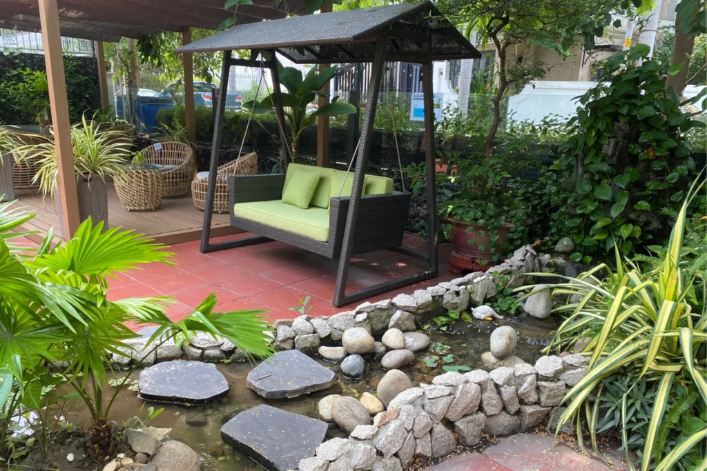 Sỏi Rải Sân Vườn: Cách Bố Trí Tạo Điểm Nhấn Độc Đáo Cho Không Gian 8 Xích đu hai chỗ ngồi đặt trên sàn gỗ cạnh hồ nước và hàng cây rợp bóng.