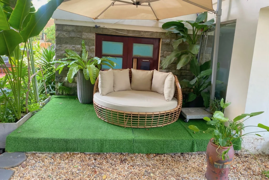 Sỏi Rải Sân Vườn: Cách Bố Trí Tạo Điểm Nhấn Độc Đáo Cho Không Gian 7 Ghế lounge tròn đặt trên nền cỏ nhân tạo, bao quanh bởi cây xanh và ô che nắng.
