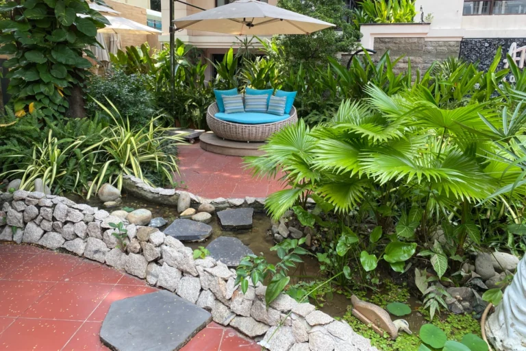 Lối đi sân vườn lát đá men theo thác nước nhỏ, tạo không gian thiên nhiên thư thái.