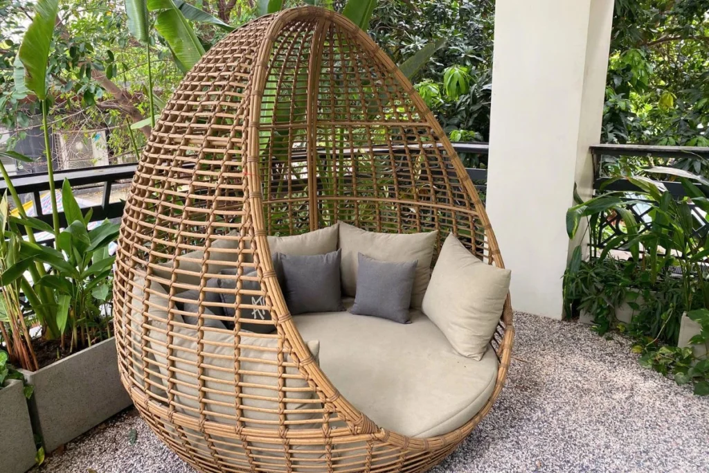 giường tắm nắng với gối và nệm, sỏi nhỏ rải xung quanh, chậu cây xung quanh ban công
