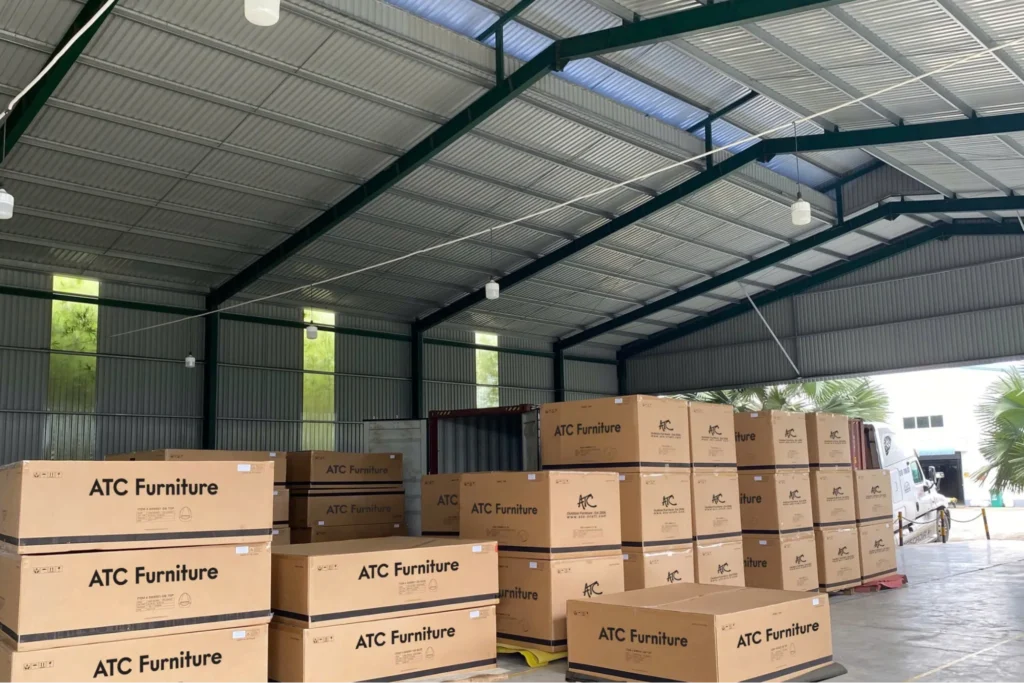 Kho thành phẩm với các thùng carton in logo ATC Furniture được đóng gói và xếp gọn gàng trên pallet, sẵn sàng cho vận chuyển.  