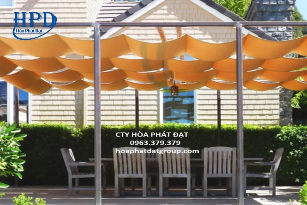 Top công ty bán dù che nắng uy tín 2025 bạn nên biết 5 Mái che xếp lớp màu cam của Hòa Phát Đạt trên khung thép vững chắc, che bộ bàn ghế ngoài trời trong sân vườn.