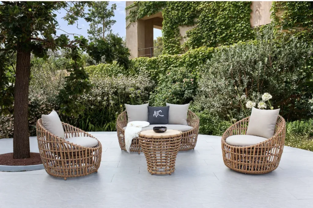 Khu ghế ngồi ngoài sân được bao quanh bởi hàng cây xanh, tạo ranh giới mềm thay cho vách cứng.