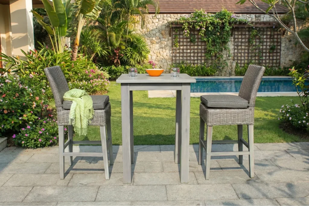 Ghế quầy bar bọc nệm đặt ngoài trời, khung gỗ kết hợp mây nhựa, đi kèm bàn bar cao trong không gian sân vườn xanh mát.