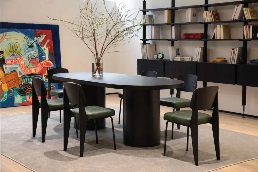 Không gian trưng bày Zero Furniture với bàn ăn tối giản màu đen, ghế bọc da xanh và kệ sách hiện đại