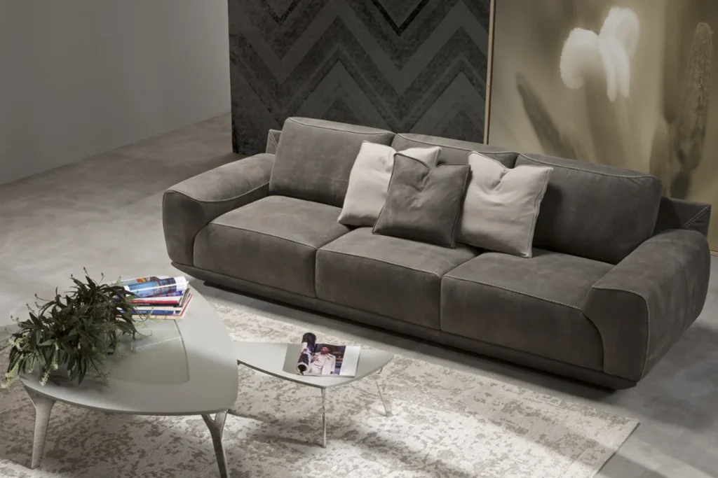 Sofa COZY màu xám trong không gian showroom hiện đại với bàn trà, thảm sáng màu và gối trang trí