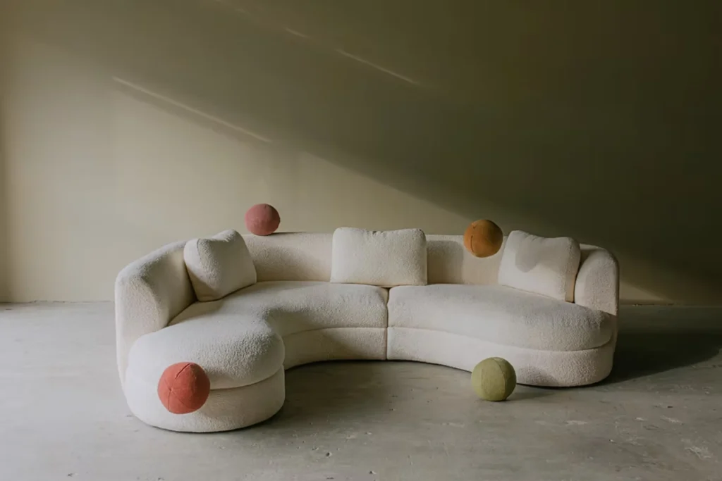 Không gian He Studio với sofa bo cong màu kem và các chi tiết trang trí nghệ thuật trong tông màu trầm