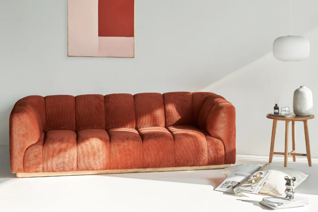 Sofa MOHO màu cam đất trong không gian phòng khách tối giản với bàn phụ gỗ và ánh sáng tự nhiên